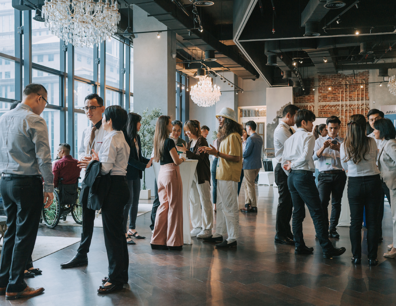 Group of people standing in a room with chandeliers hanging from the ceiling